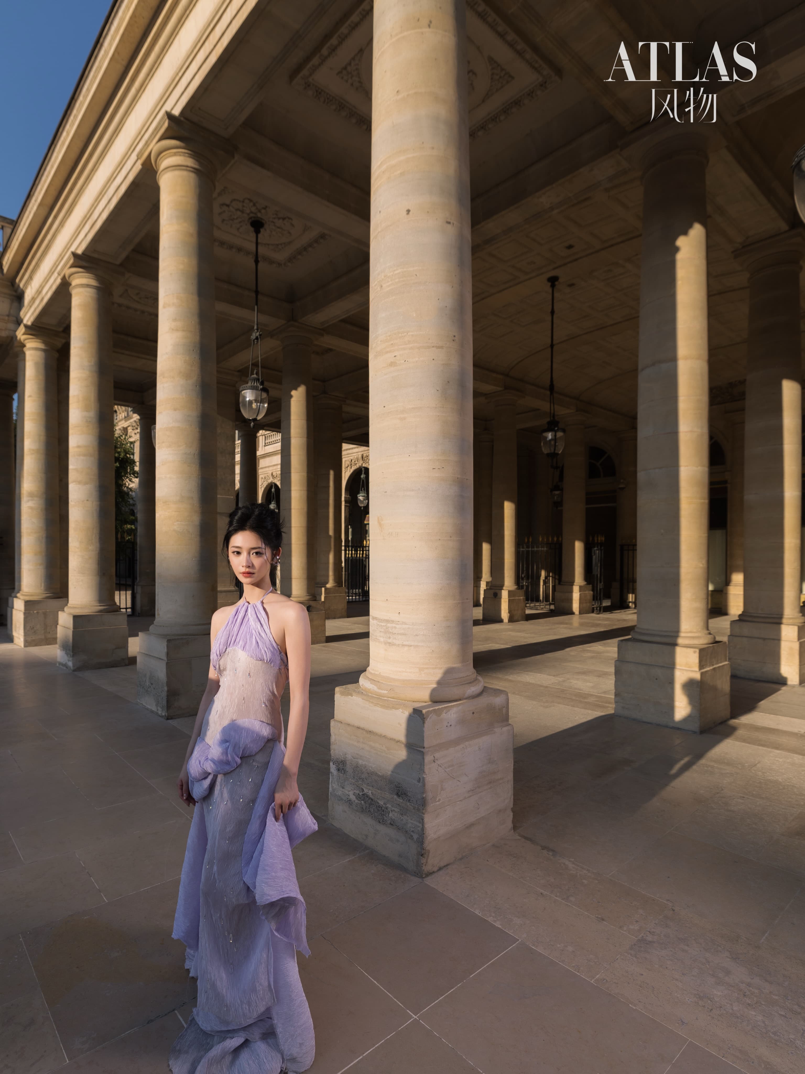 Zhou Jieqiong standing among the long shadows and stone columns of a Paris colonnade.