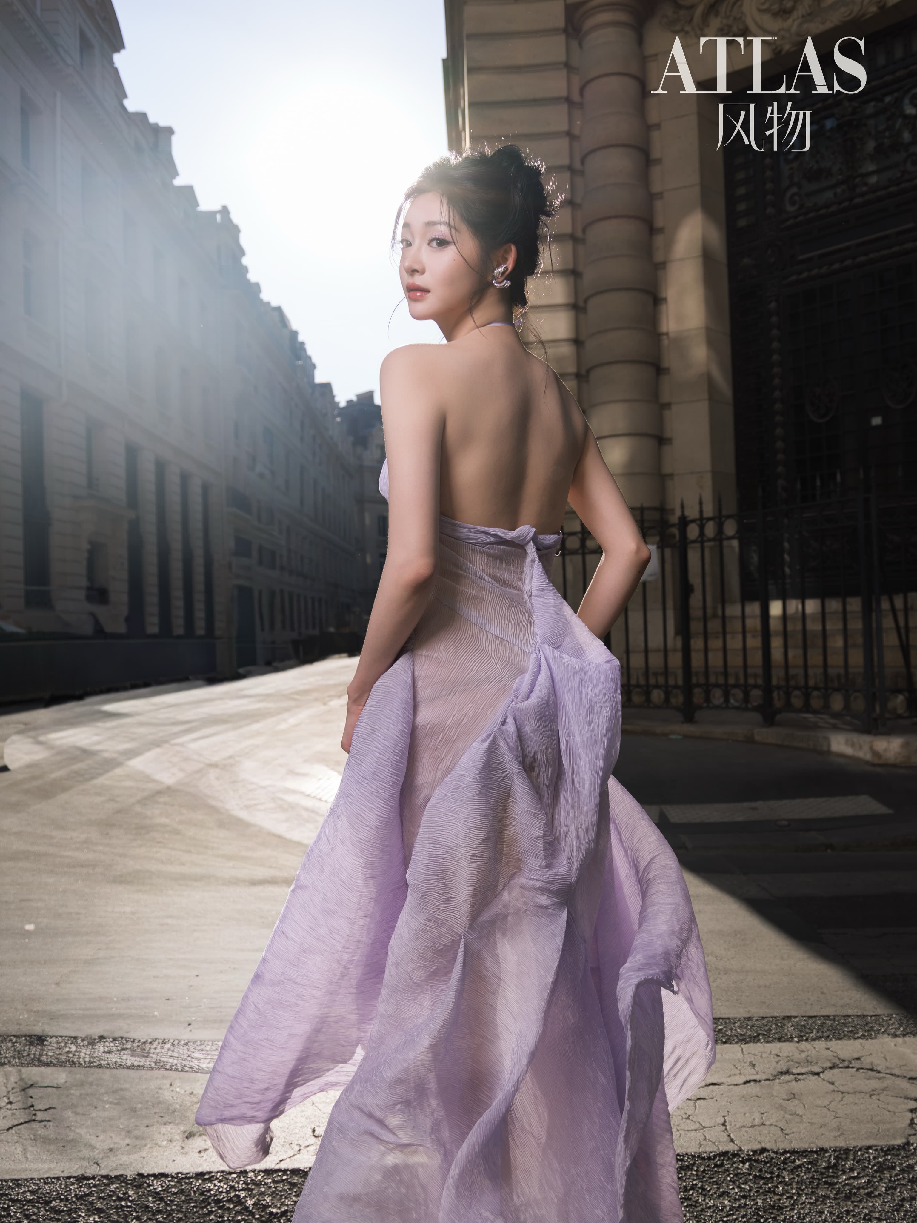 Zhou Jieqiong looks back on a sunlit Paris street as the lavender skirt moves behind her.
