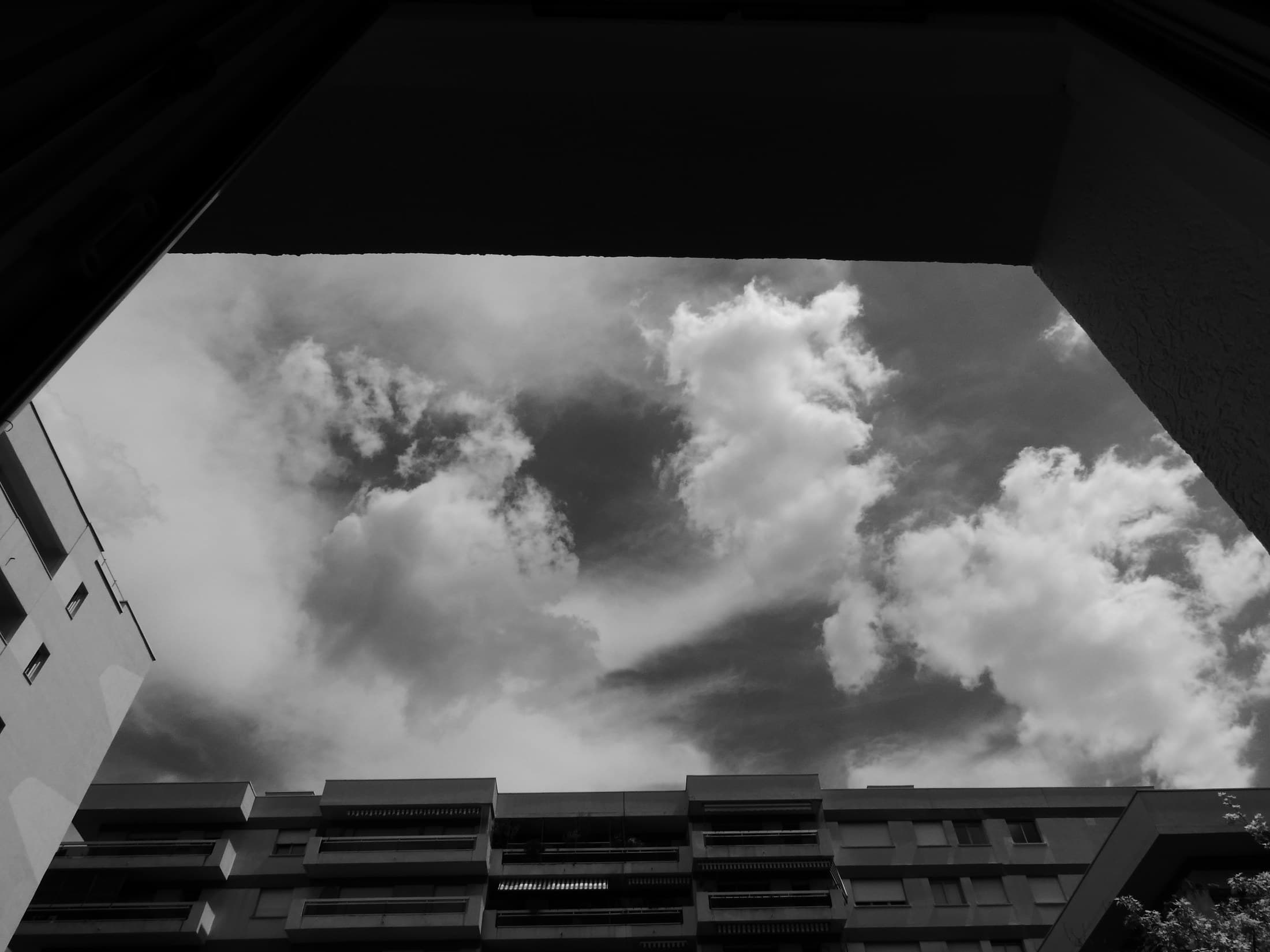 Clouds framed by a dark architectural overhang.