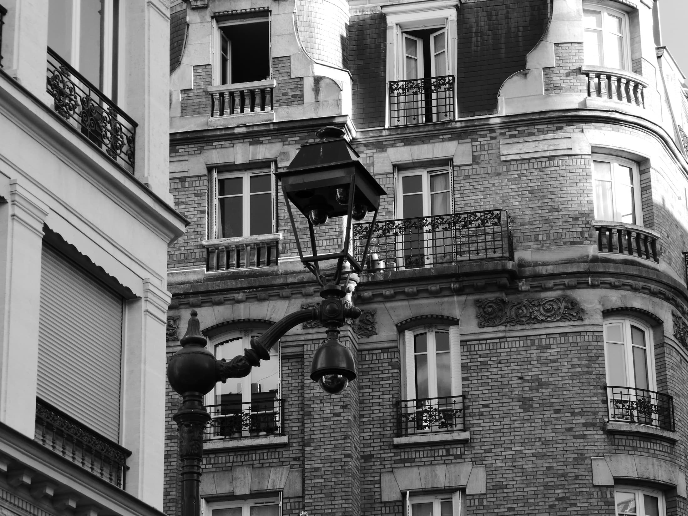 A Paris facade with balconies and a street lantern in black and white.
