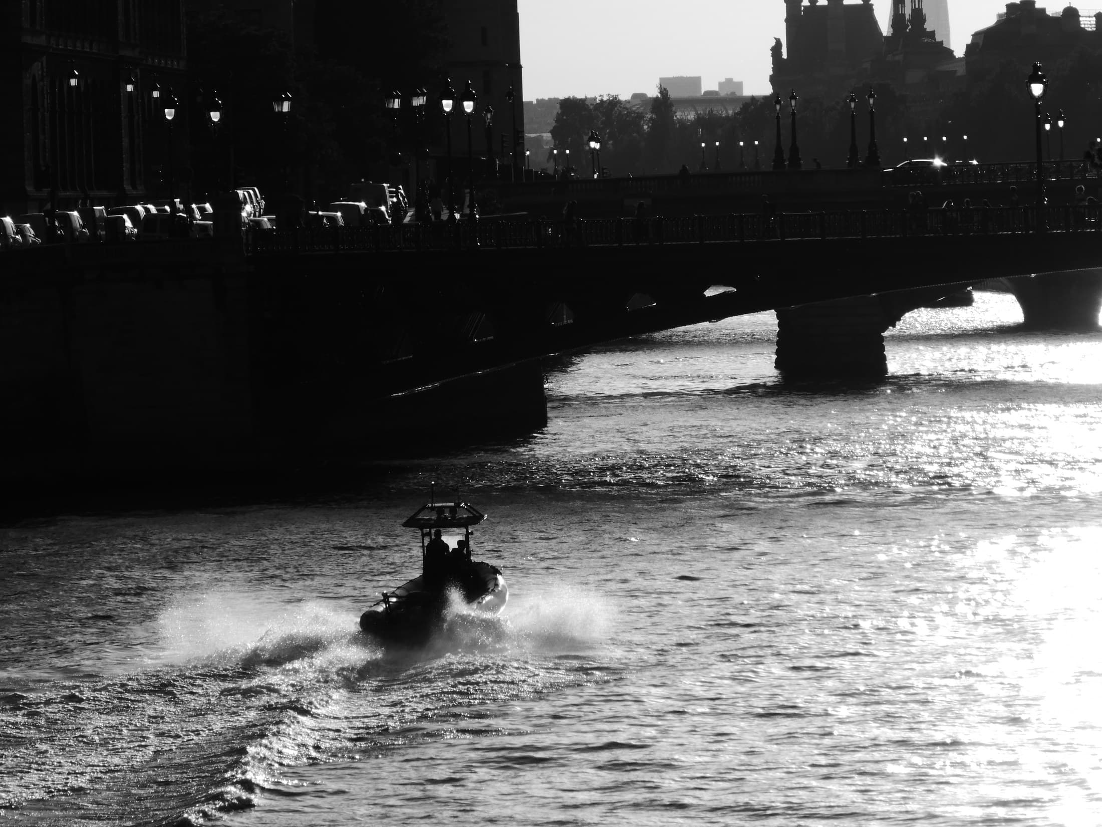 A boat moving across the Seine in black and white.