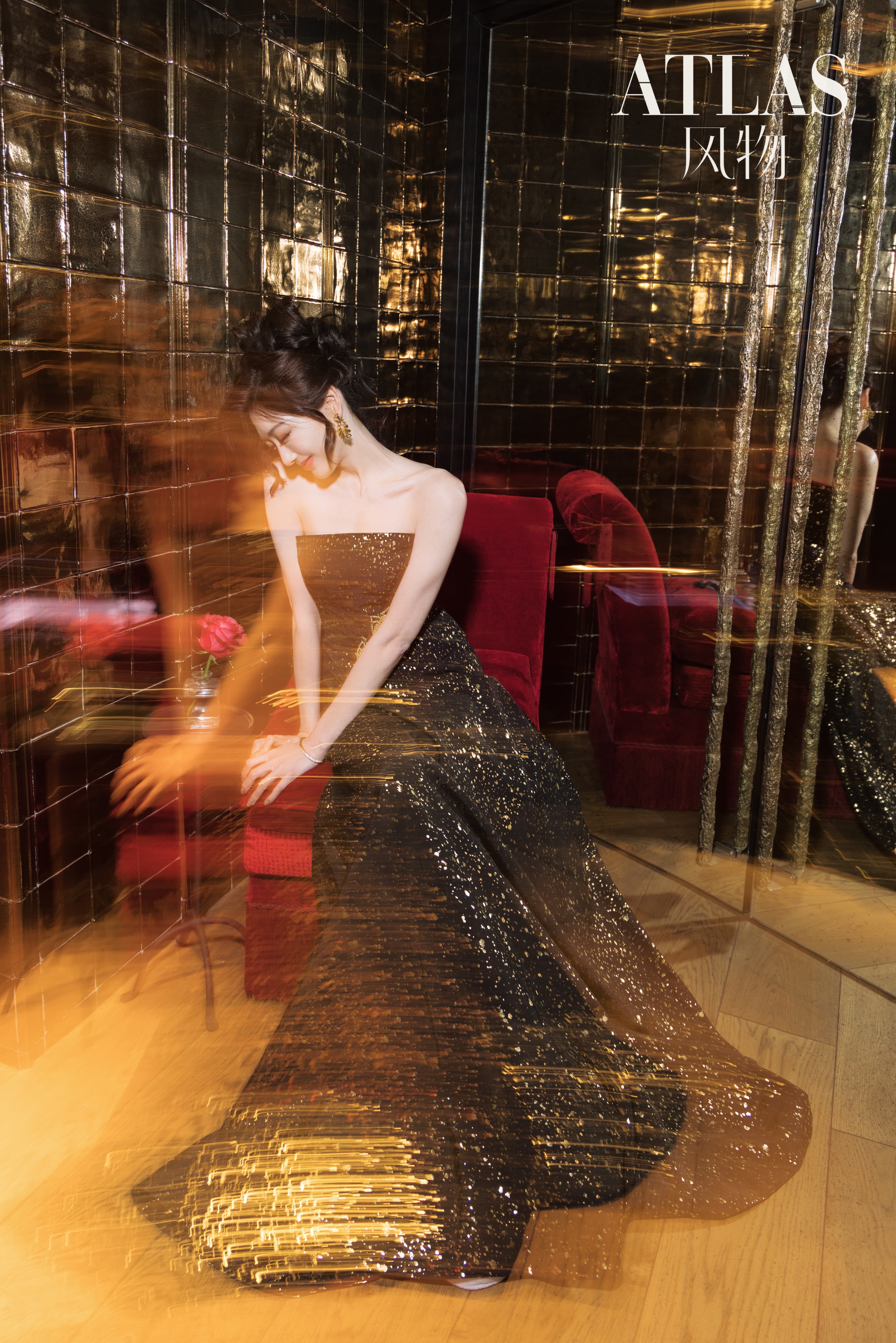 Sun Leyan seated in a reflective interior with red velvet and motion blur.