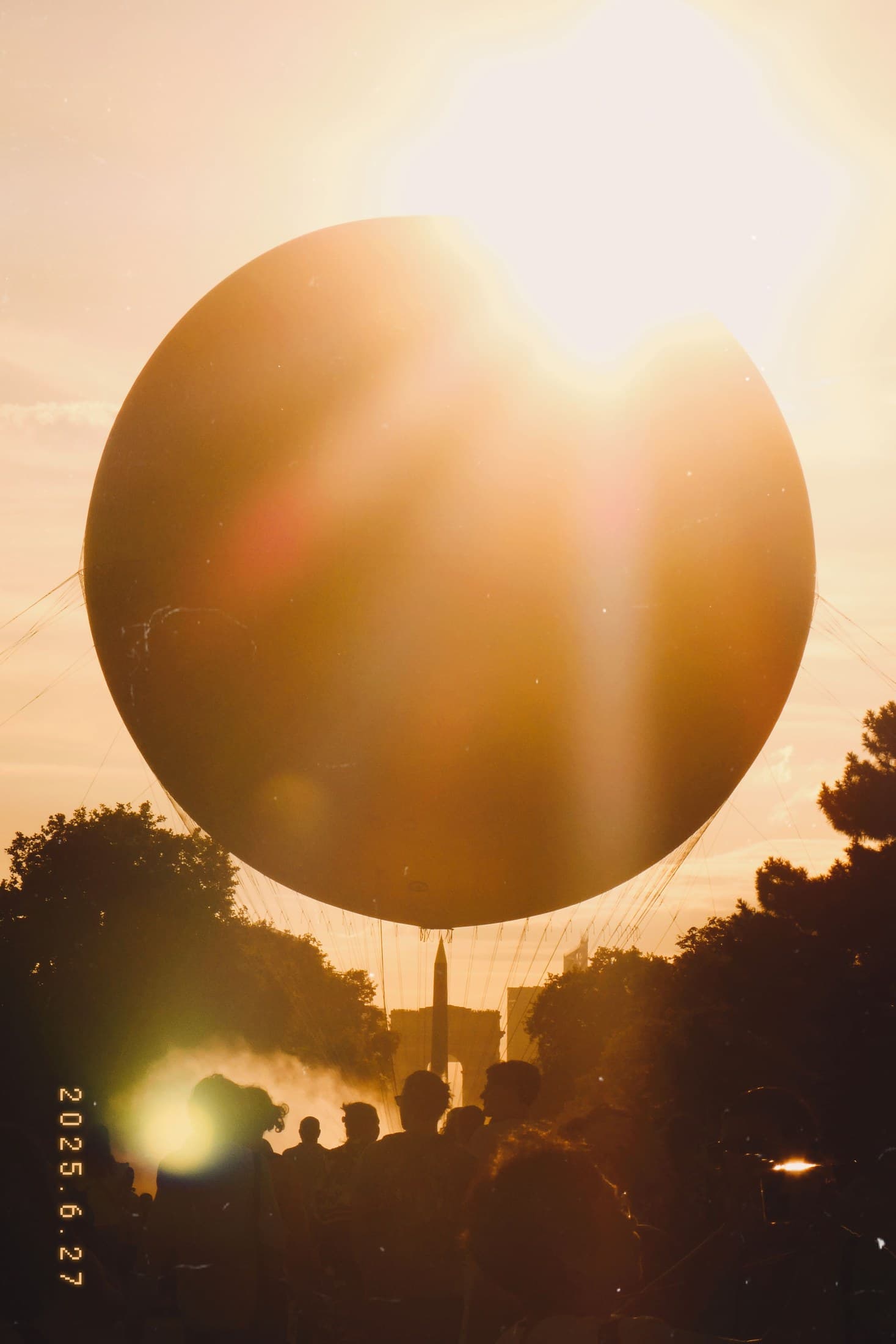 A glowing balloon-like form suspended against sunset light in Paris.